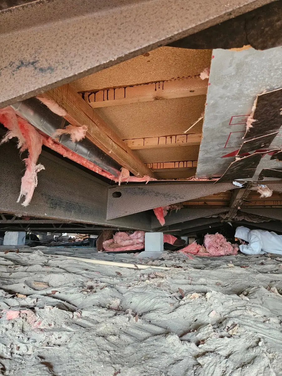 Old bottom board and insulation piled on a tarp beside the home for haul-away