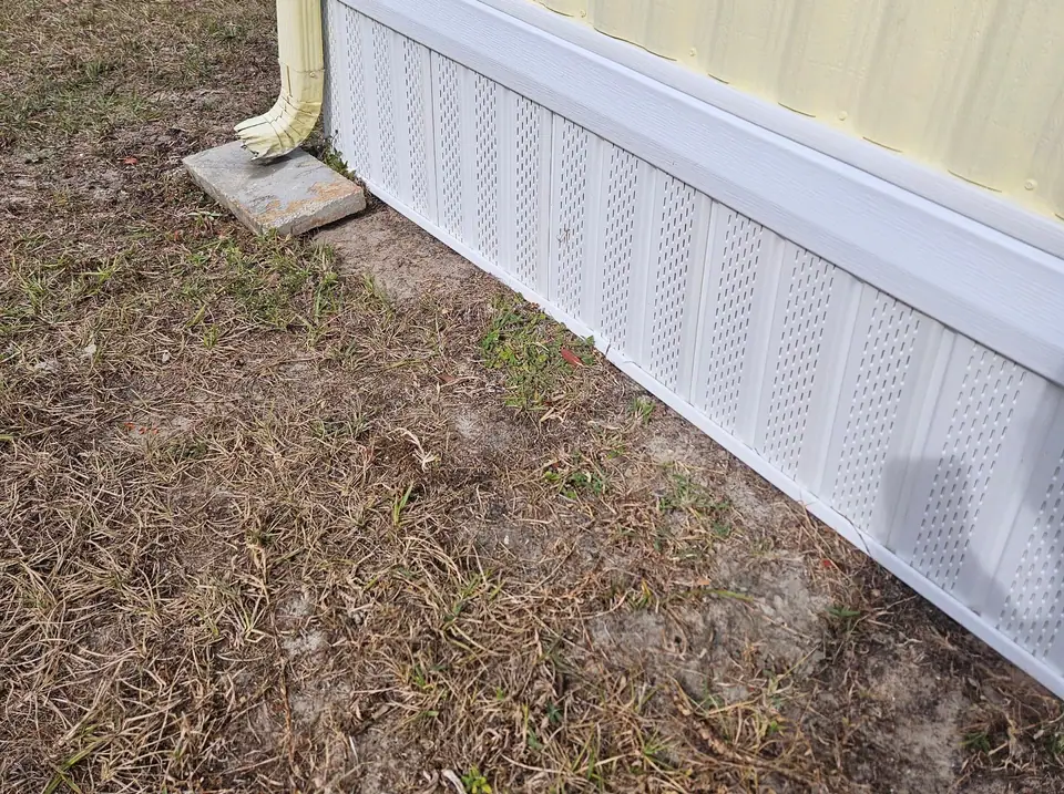 New white vented underpinning along the corner of a cream manufactured home