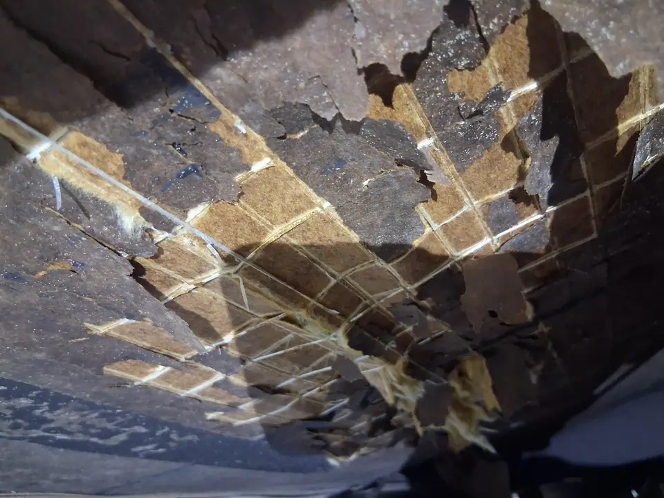 Crumbling water-damaged decking and belly board seen from under the home