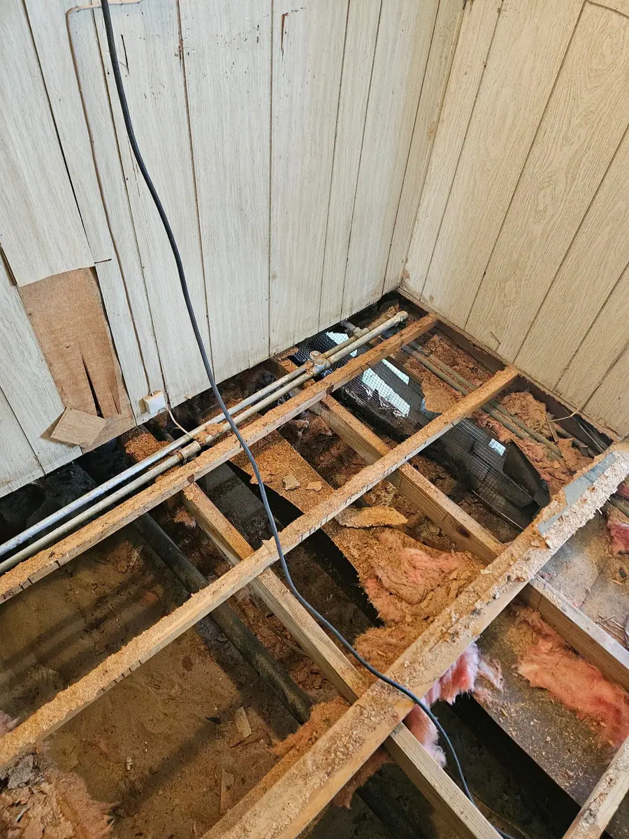 Manufactured home floor opened from above, joists and old insulation showing