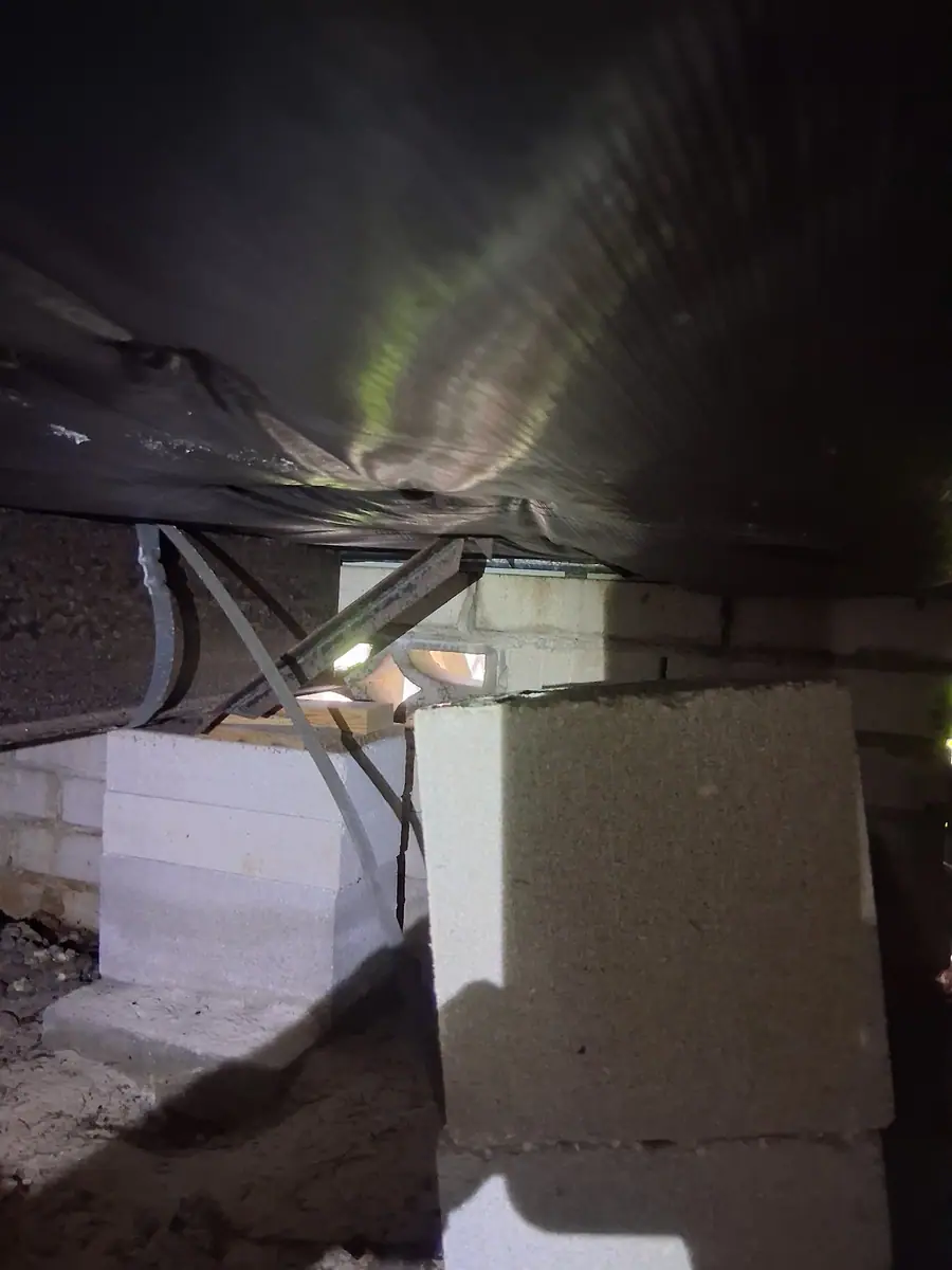Concrete block pier with a cap under black belly wrap on a manufactured home