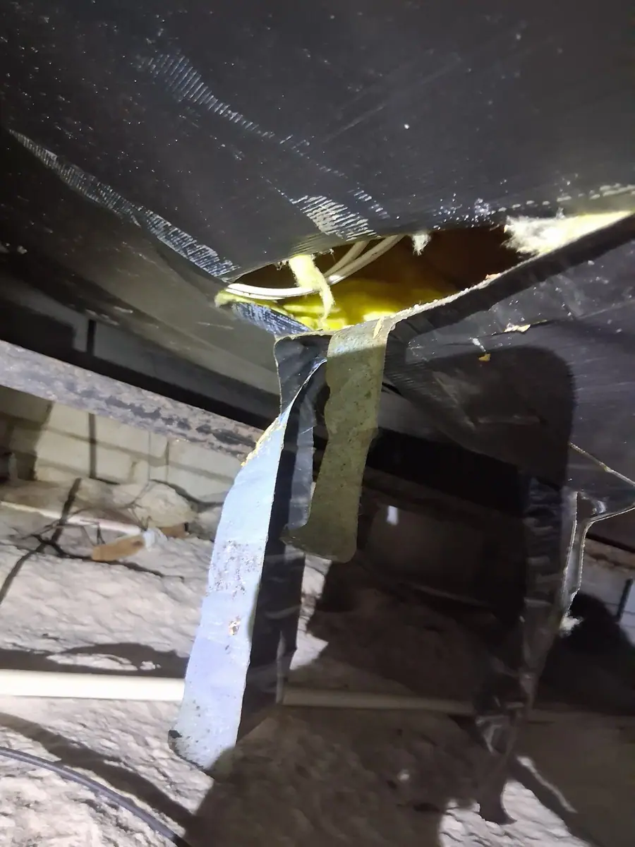 Belly torn open next to a block pier with insulation spilling out