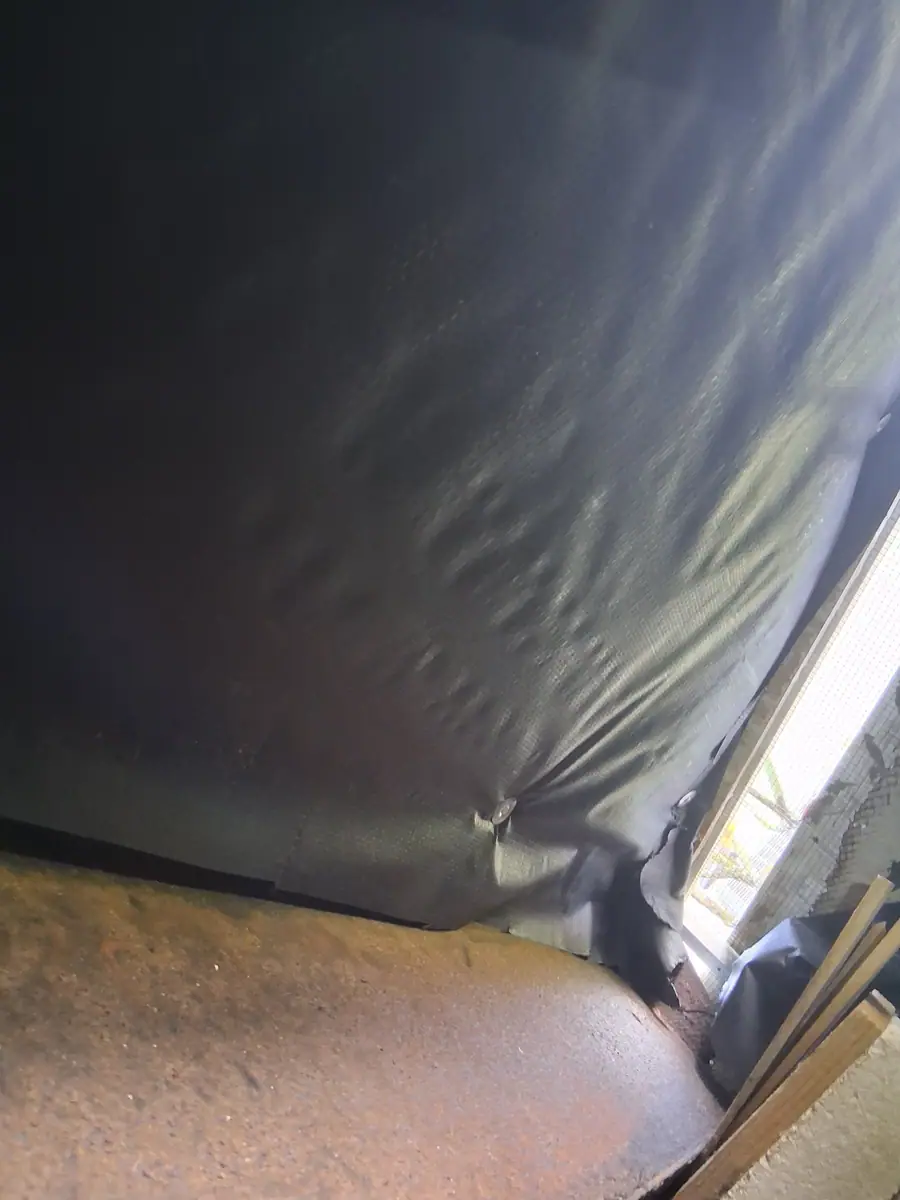 Black belly wrap stretched under the floor, seen across the crawl space