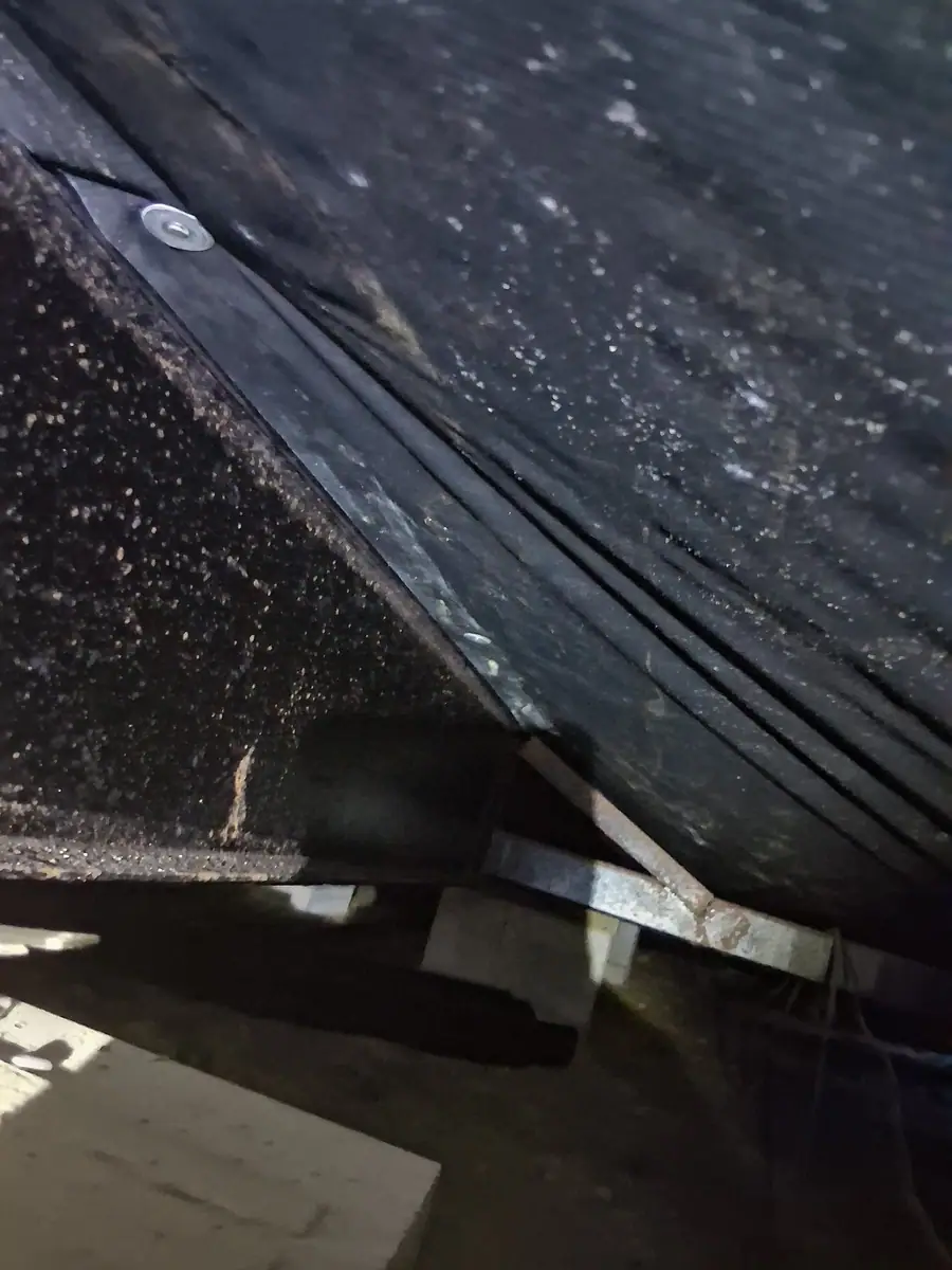 Rows of fasteners holding black belly wrap up under the floor