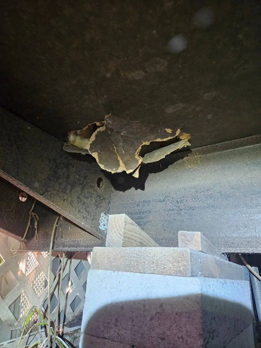Torn bottom board above a block pier, with lattice skirting behind