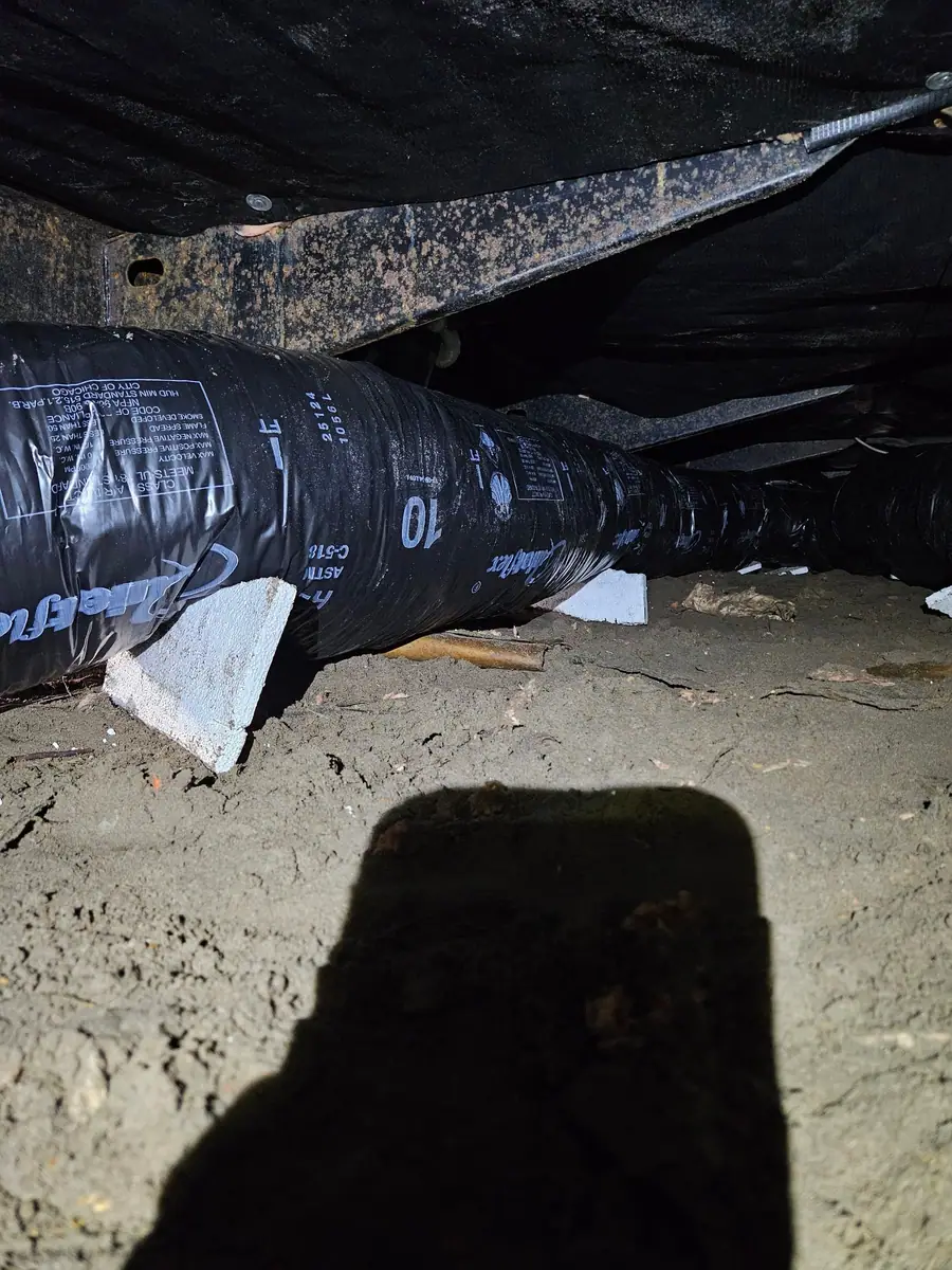 Insulated flex duct set on a block under black belly wrap