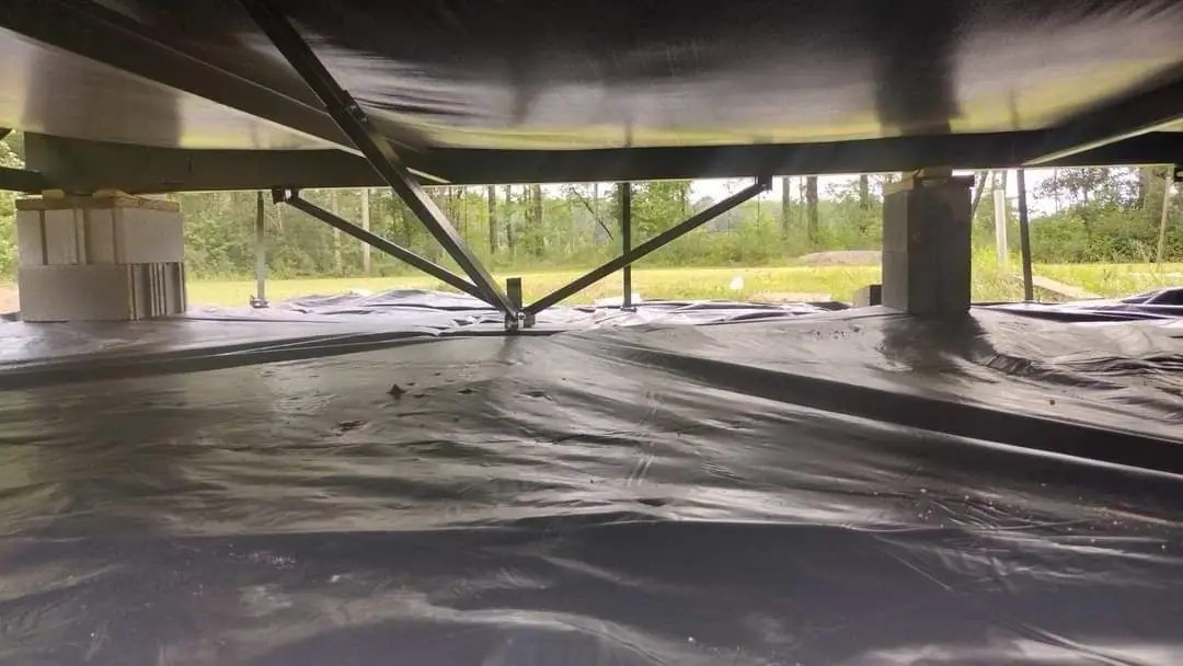 New moisture barrier sheeting over the soil under a manufactured home, with steel stabilizer struts