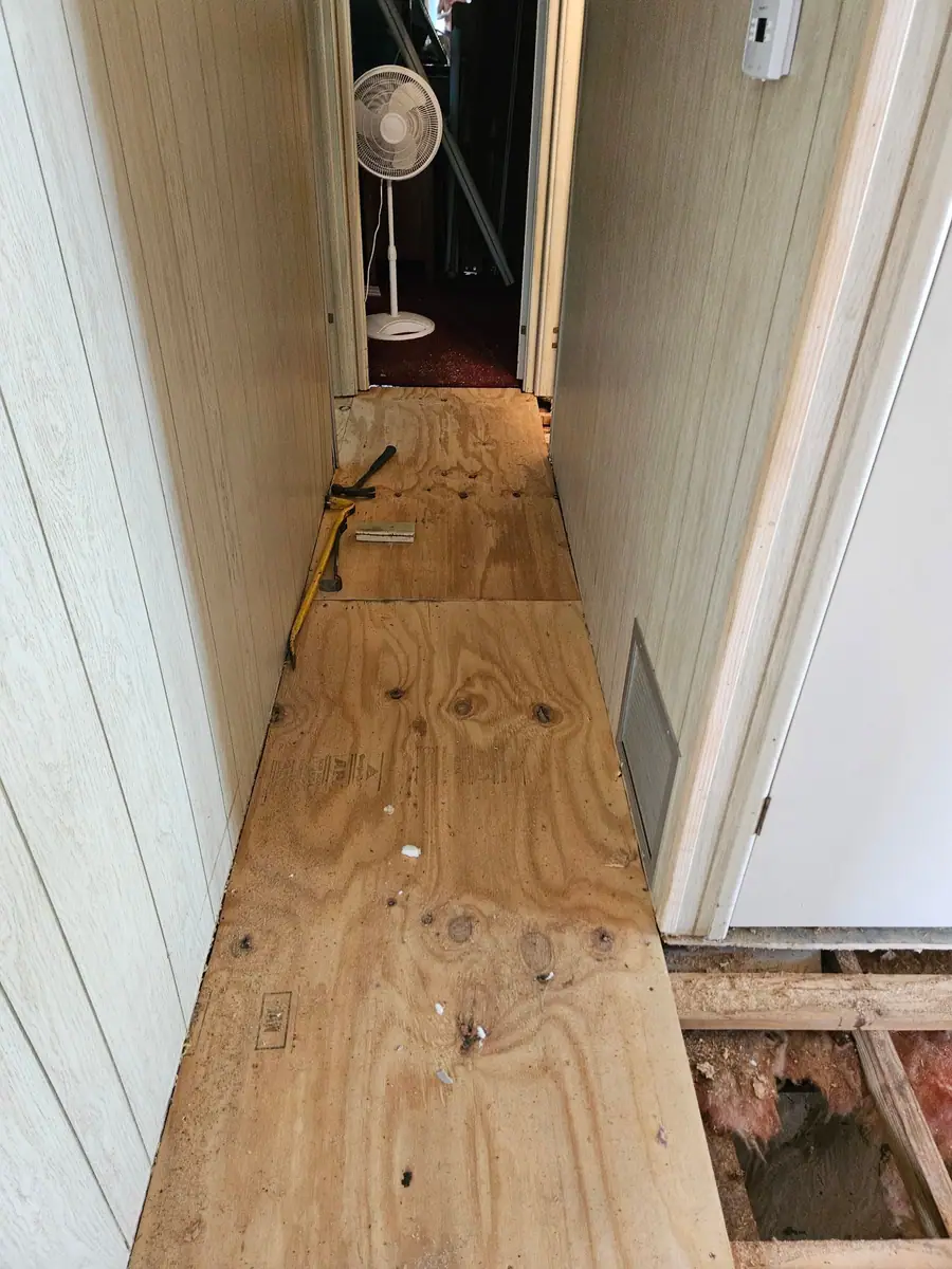 New plywood decking down a hallway after a soft floor repair in a manufactured home