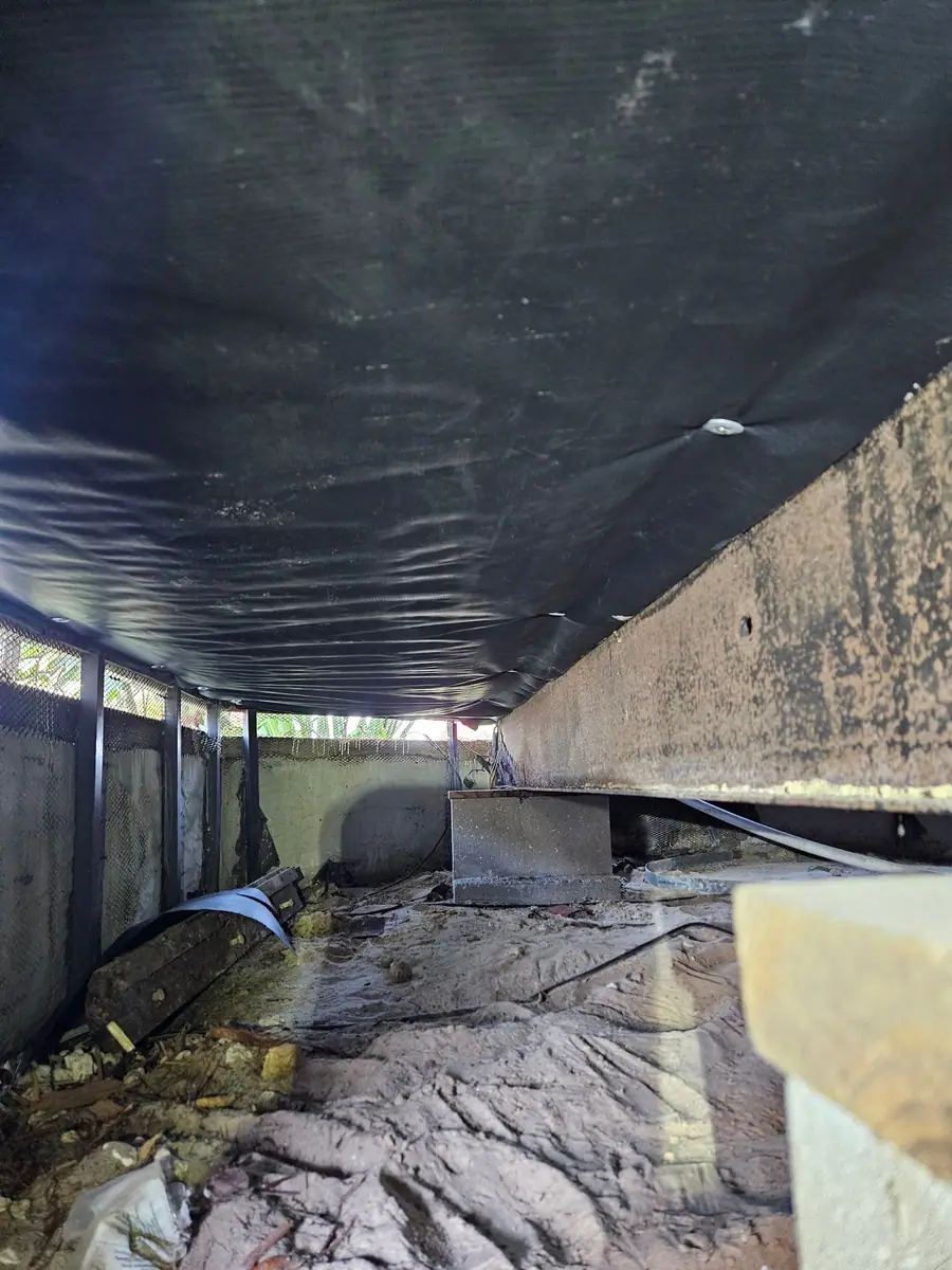 Looking down the length of a crawl space under new black belly wrap
