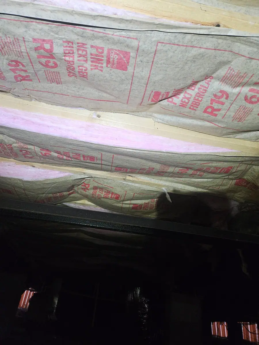 New R-19 kraft-faced insulation batts installed between floor joists under a manufactured home