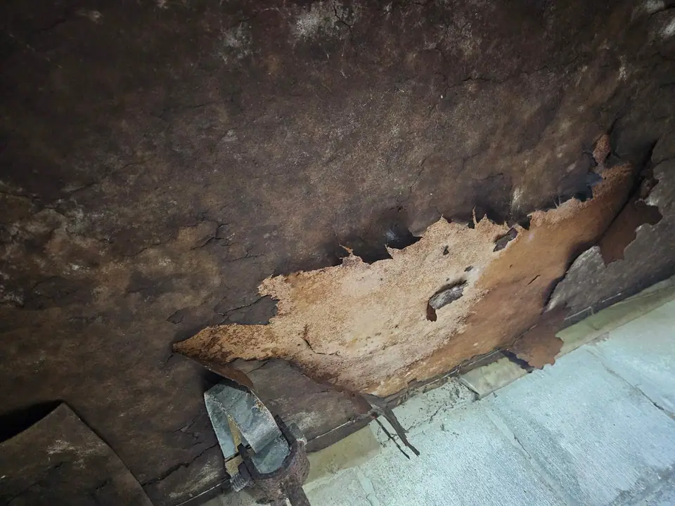 Rotted fiberboard bottom board hanging under an older mobile home