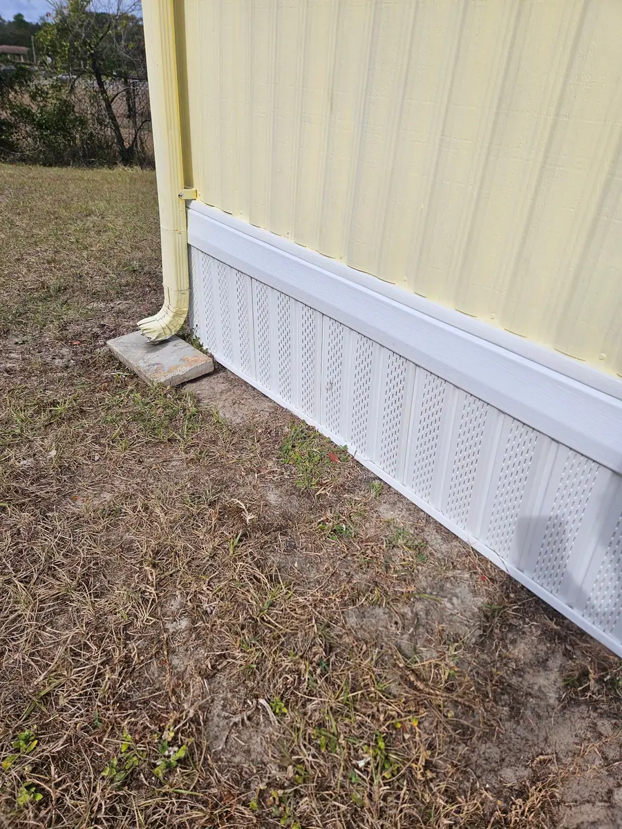 New white vented underpinning at the corner of a cream manufactured home