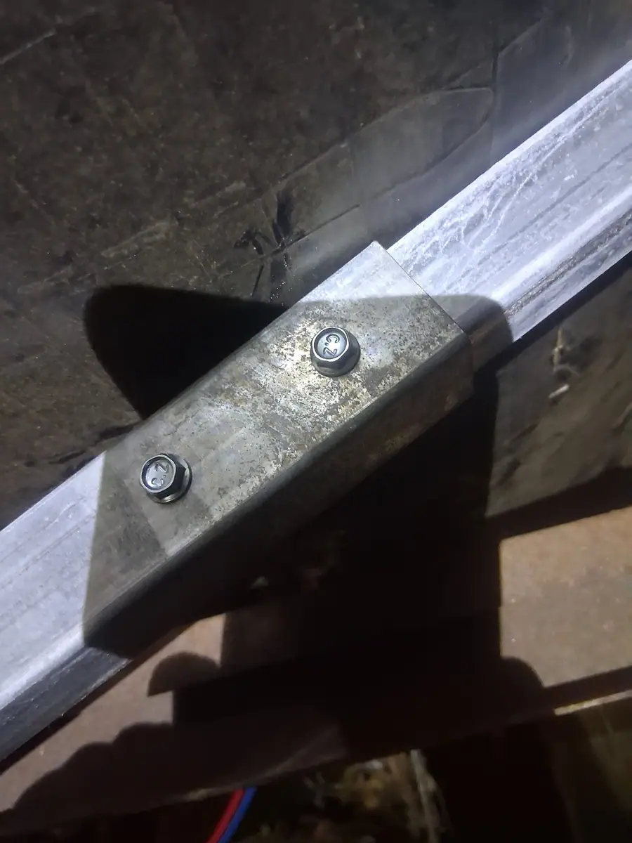 Steel stabilizer strut bolted to the I-beam under a manufactured home