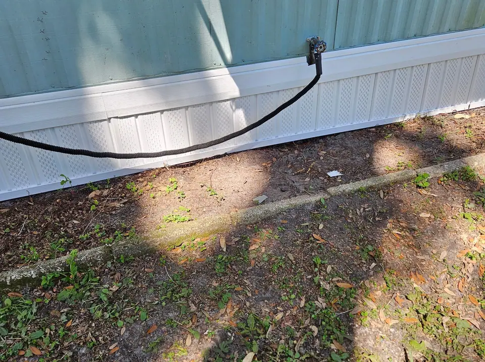 A teal manufactured home with finished white skirting along the lawn