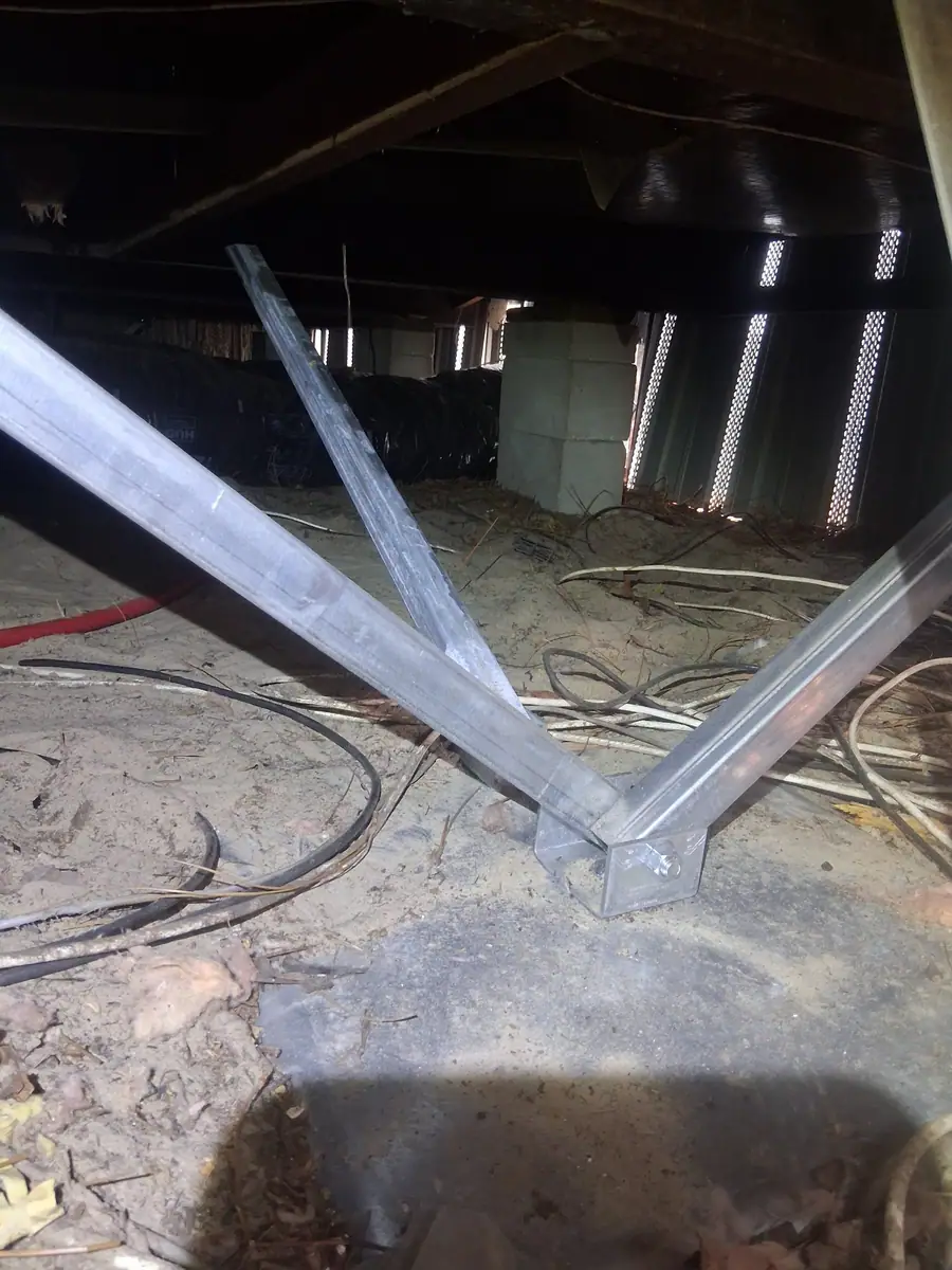 Steel stabilizer struts on a ground pan with block piers behind